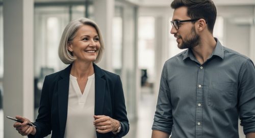 Eine erfahrene Mentorin im Gespräch mit einem jungen Mitarbeiter in einem modernen Büro.