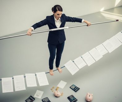 Ein Freelancer balanciert auf einem Seil aus Verträgen, um das Risiko der Scheinselbstständigkeit zu vermeiden.